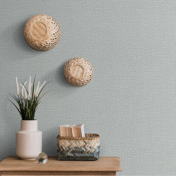 Woven baskets on a textured gray Erismann wallpaper with a wooden shelf and decorative items.