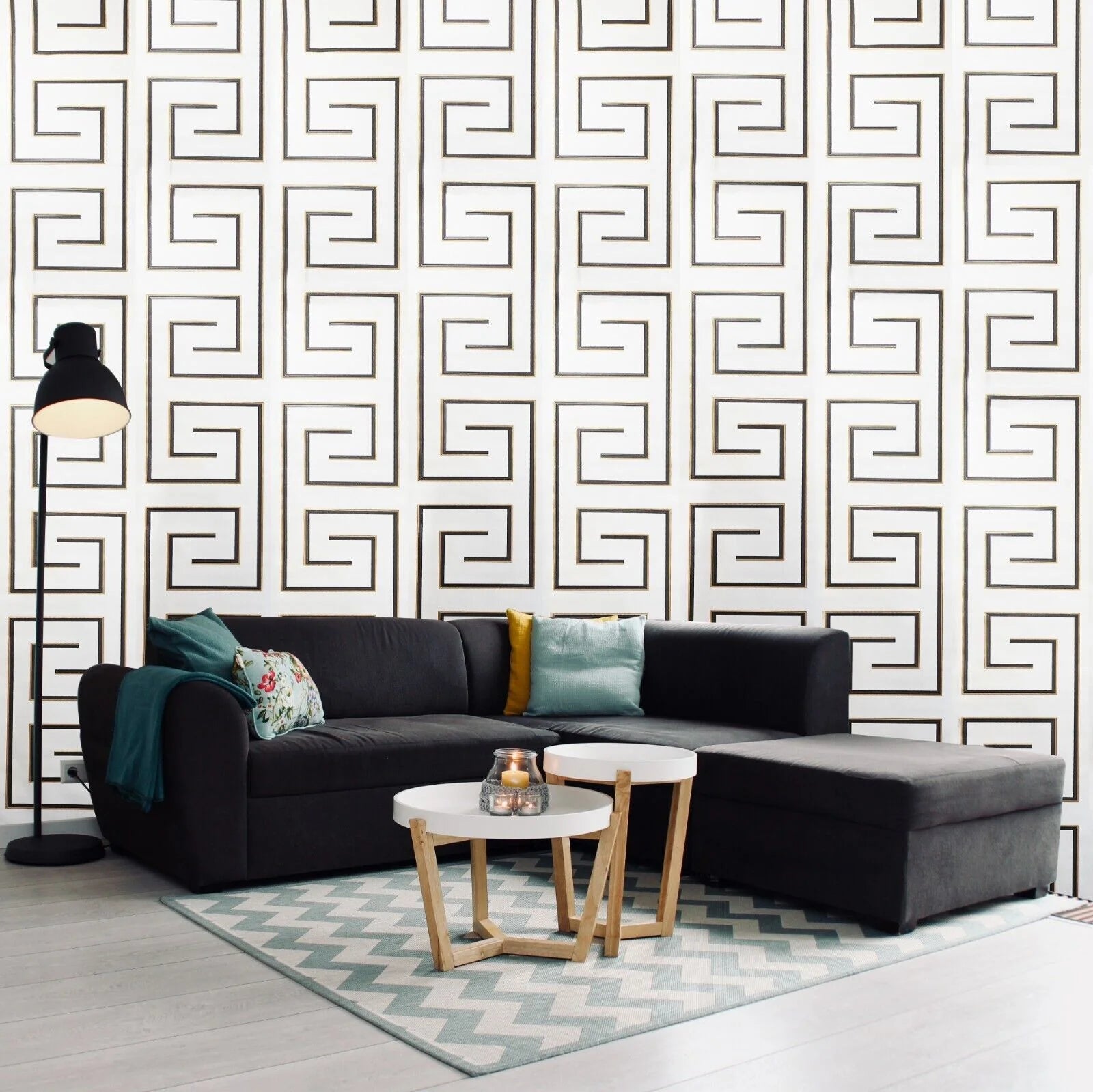 Modern living room with a black sectional sofa, patterned rug, and geometric wall design.