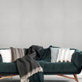 Green sofa with decorative pillows and a throw blanket against a gray textured wall.