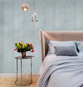 Bedroom with geometric wallpaper, bed, and side table with flowers.