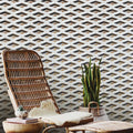 Wicker chair with ottoman and small table against a geometric patterned wall.