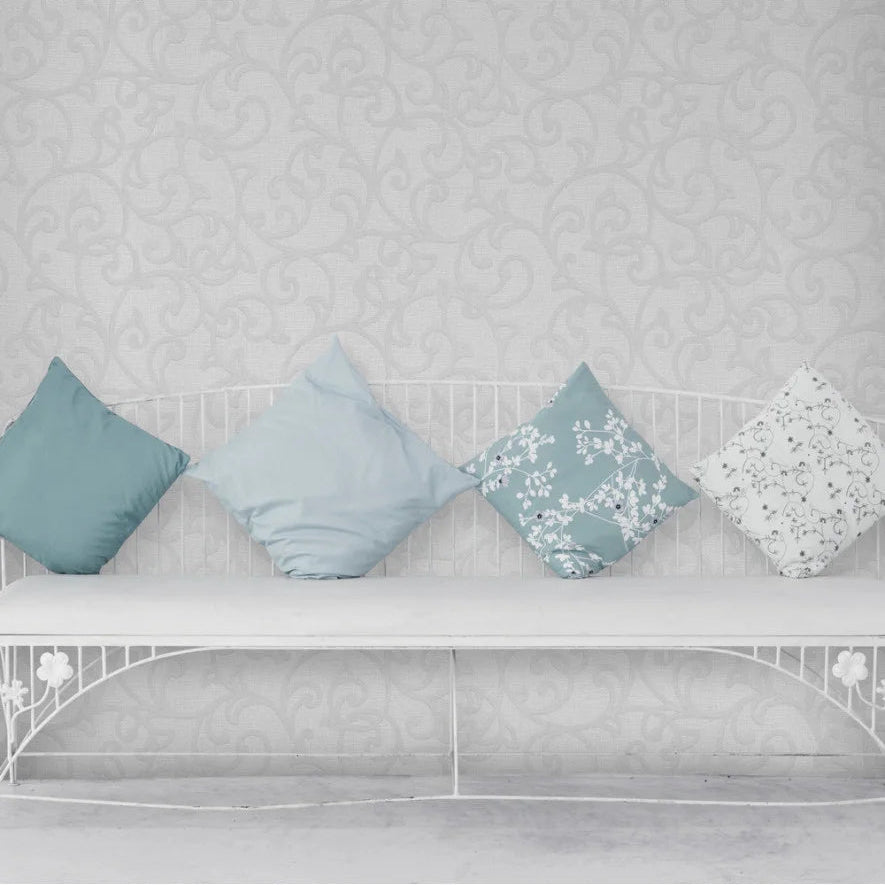 Decorative pillows on a white bed against a patterned Erismann traditional wallpaper.