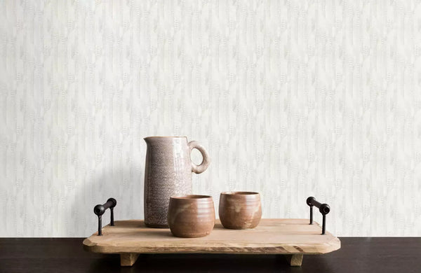 RC19068 Roberto Cavalli wallpaper behind a rustic wooden serving tray with black metal handles holds a speckled beige ceramic pitcher and two brown ceramic cups.