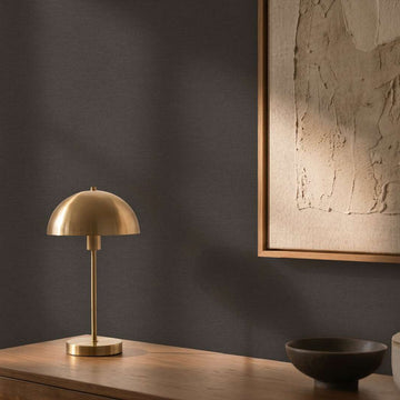 AS Creation Cosiness 792432 black textured wallpaper behind a wooden sideboard with a brass dome table lamp, framed artwork, and a ceramic bowl with lidded jar.