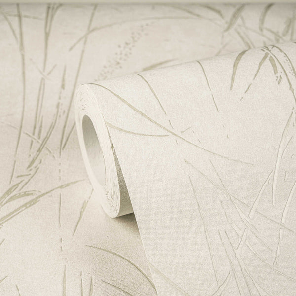 AS Creation Cosiness 792821 wallpaper roll with an abstract grass like pattern in Cream, Metallic, and White, shown partly unrolled on a matching surface.