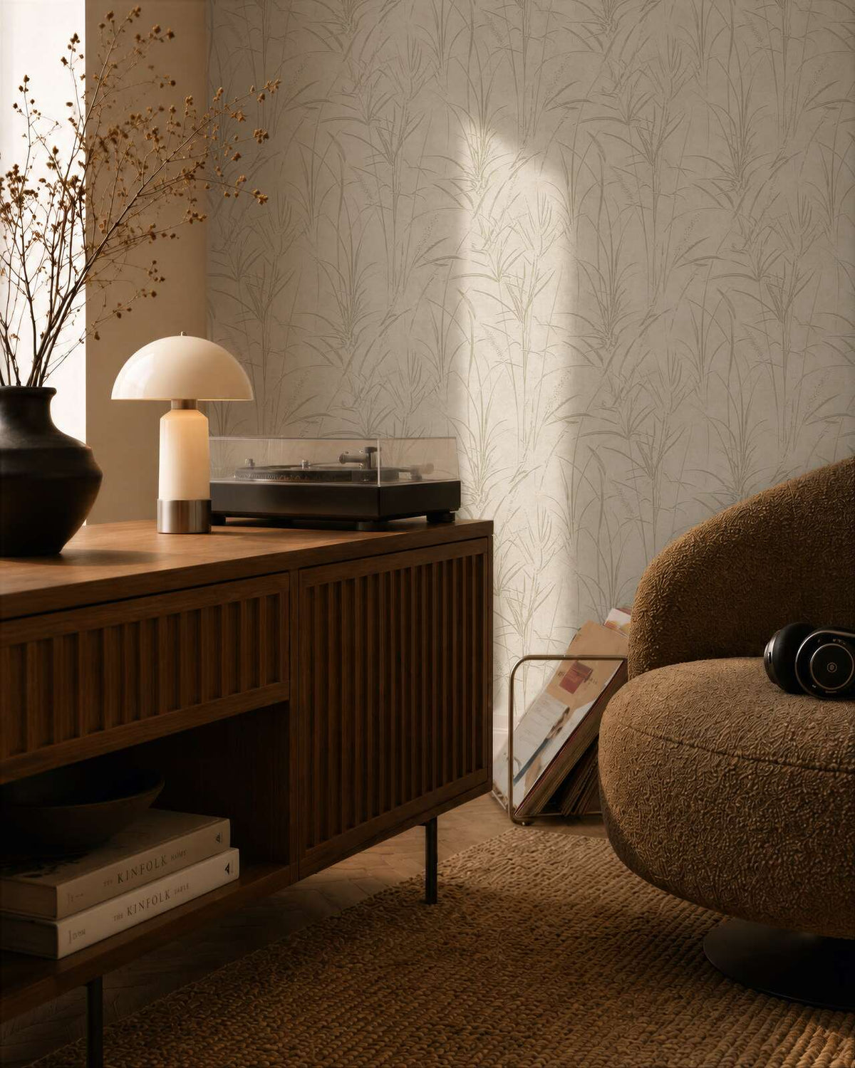 AS Creation Cosiness 792821 living room with Cream and White wallpaper featuring a subtle botanical grass motif with Metallic accents, beside a wooden sideboard and a rounded armchair.