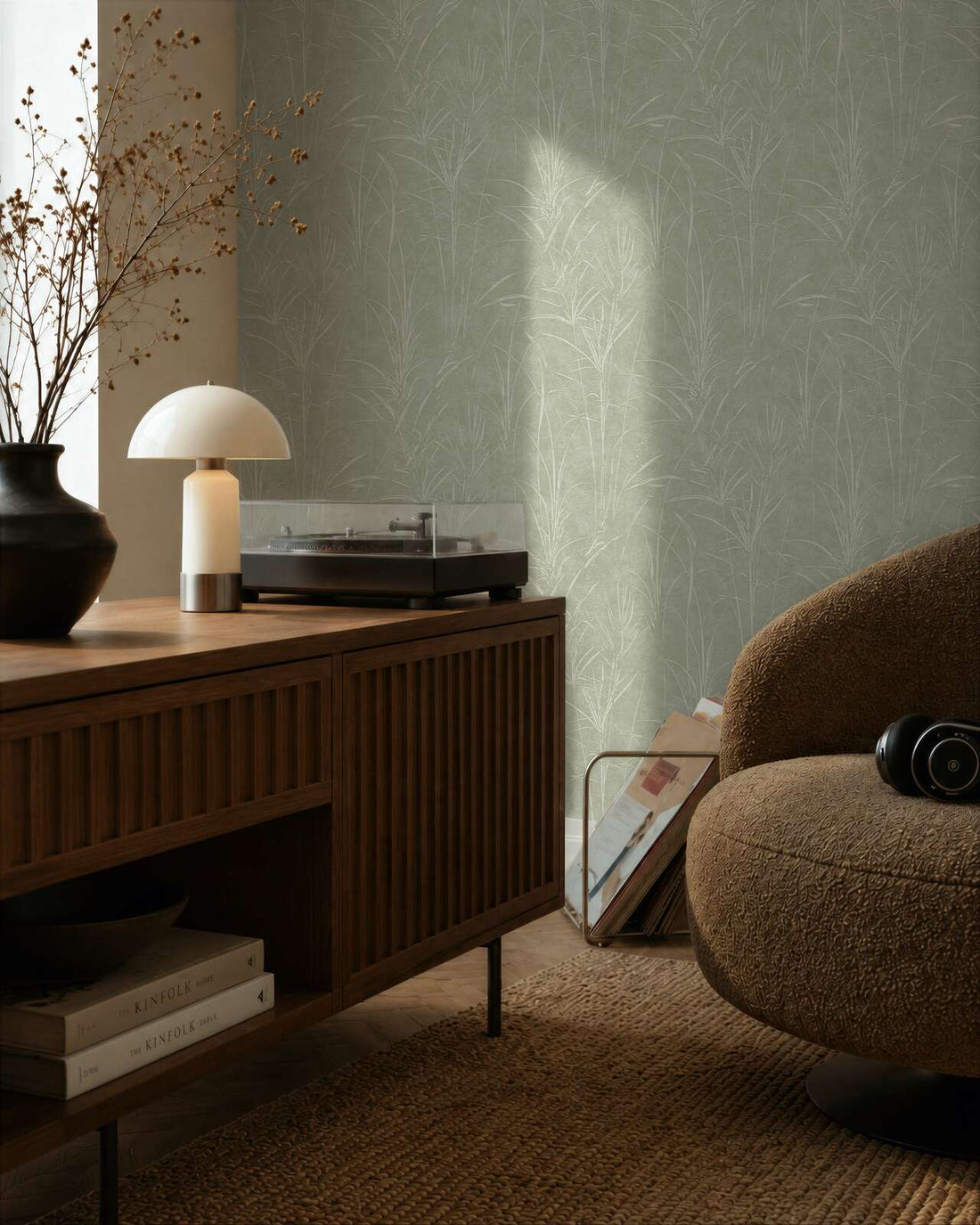 AS Creation Cosiness 792822 living room with Green, Metallic botanical wallpaper behind a wooden sideboard and a rounded lounge chair.