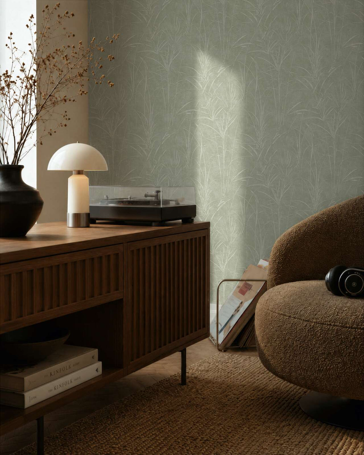AS Creation Cosiness 792822 living room with Green, Metallic botanical wallpaper behind a wooden sideboard and a rounded lounge chair.