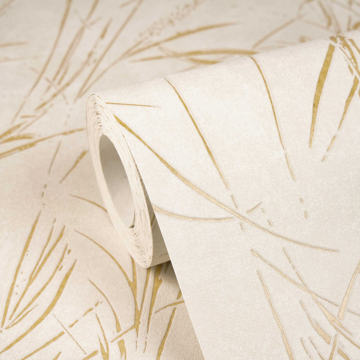 AS Creation Cosiness 792823 close up of a wallpaper roll on a matching sheet showing a linear grass like motif in the Brown, Cream, Metallic colorway.