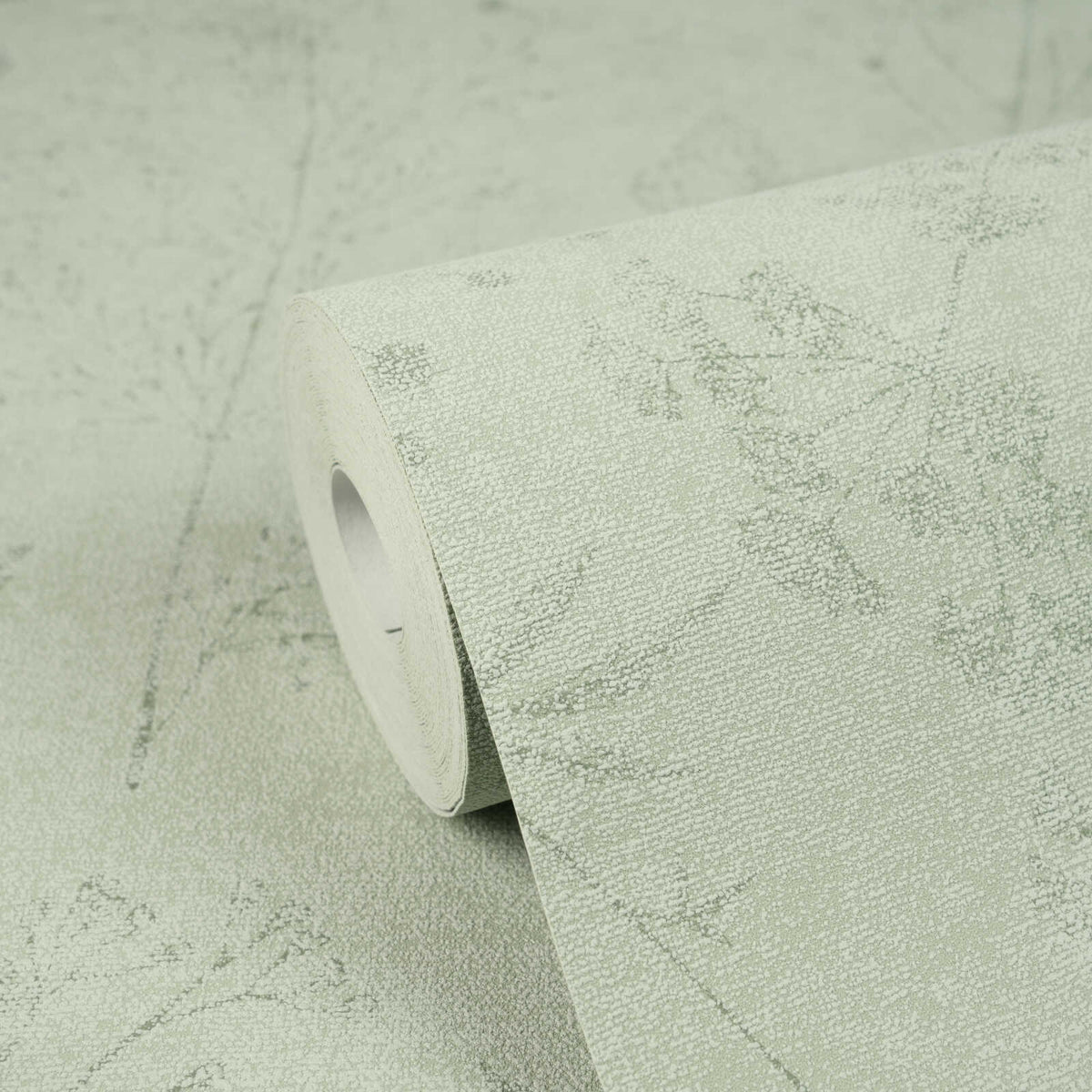 AS Creation Cosiness 792833 studio close up of a wallpaper roll resting on matching unrolled, featuring a delicate botanical silhouette pattern with a fine speckled background.