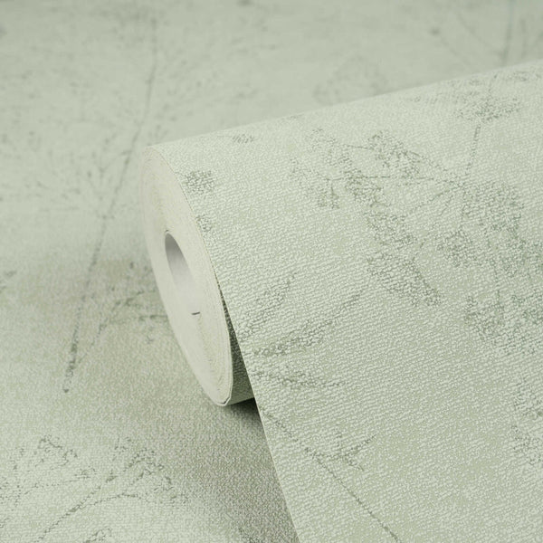 AS Creation Cosiness 792833 studio close up of a wallpaper roll resting on matching unrolled, featuring a delicate botanical silhouette pattern with a fine speckled background.