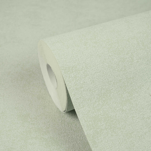 AS Creation Cosiness 792842 green speckled wallpaper roll resting on a matching unrolled sheet.