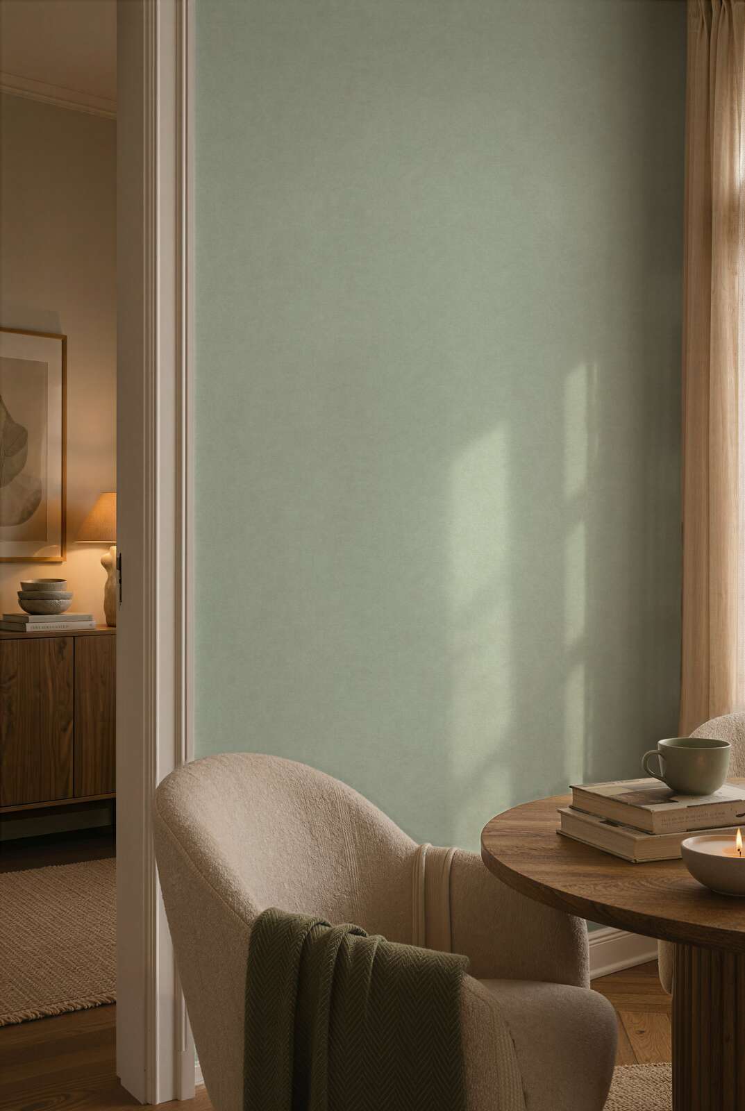 AS Creation Cosiness 792842 dining room with Green wallpaper on a sunlit wall, shown with a round wooden table and an upholstered chair.