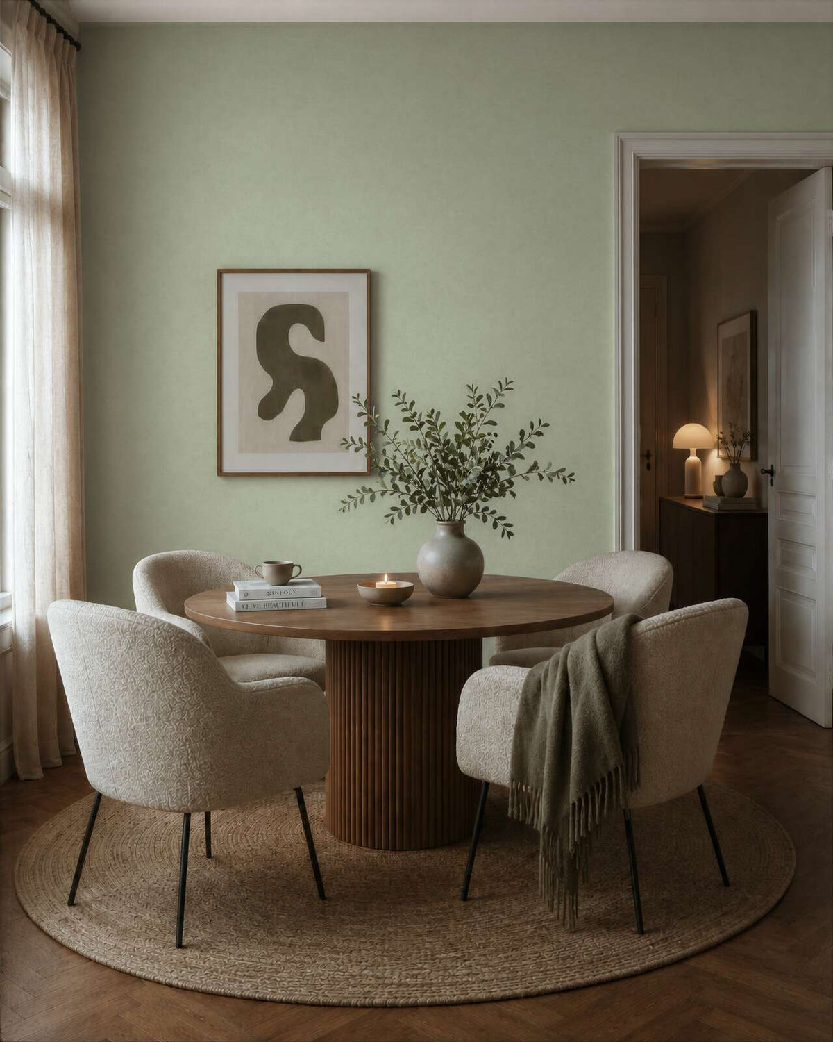 AS Creation Cosiness 792842 dining room with Green wallpaper behind a round wooden table and upholstered chairs.