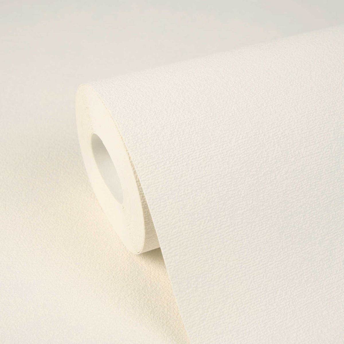 AS Creation Cosiness 792844 close up of a Cream wallpaper roll with a fine, subtle texture resting on a matching sheet.