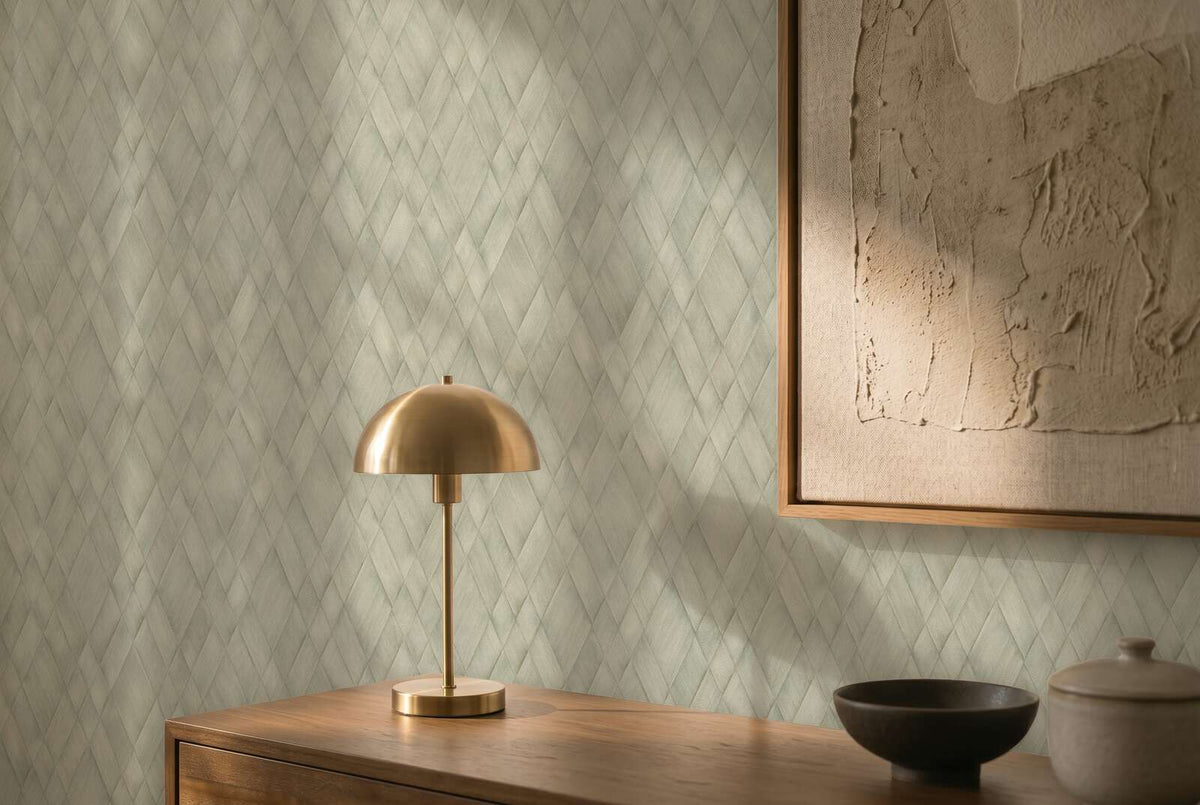 AS Creation Cosiness 793136 green wallpaper with a subtle diagonal diamond pattern behind a wooden console with a brass dome table lamp, framed textured art, and two small ceramic pieces.