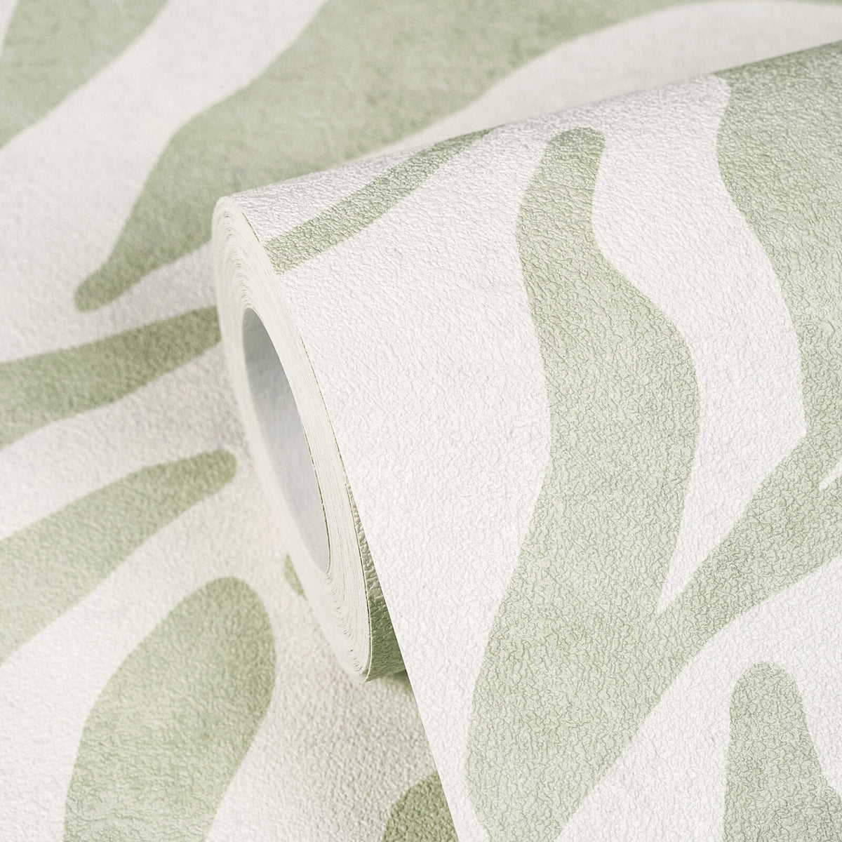 AS Creation Cosiness 793142 close up of a wallpaper roll showing an abstract wavy pattern in Green, partially unrolled on the matching surface.
