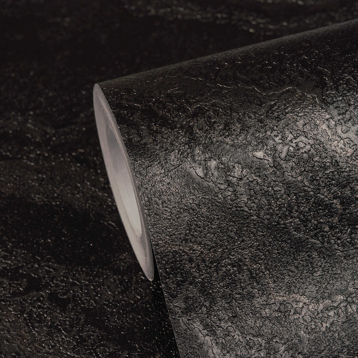 AS Creation Cosiness 793163 black, Metallic wallpaper roll with an irregular organic pattern, shown on a matching surface.