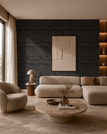 AS Creation Cosiness 793163 living room featuring a black and metallic wavy pattern wallpaper behind a sofa and round coffee table.