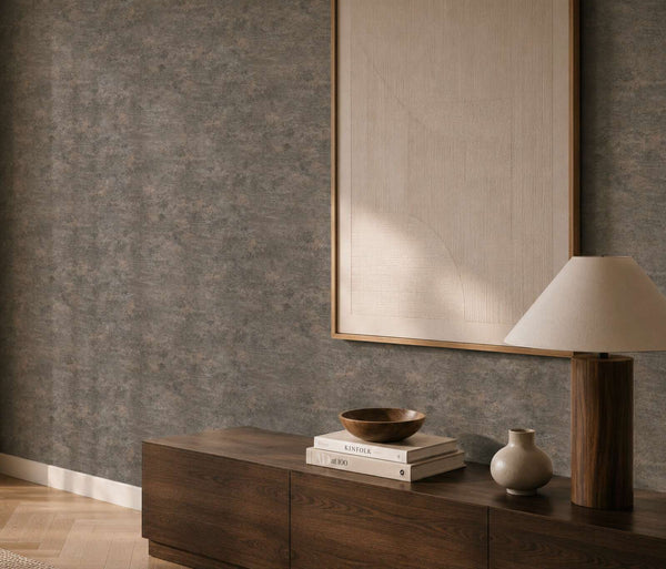 AS Creation Cosiness 793186 living room with black, grey, and metallic wallpaper featuring a subtle mottled look, shown behind a wooden sideboard and a table lamp.