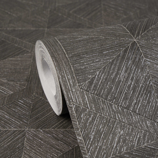 AS Creation Cosiness 793196 close up of a wallpaper roll on matching unrolled, showing a geometric pattern of angled lines forming triangles and diamonds in Brown, Grey, Metallic.