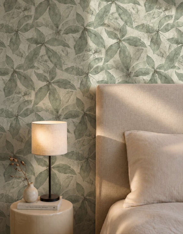 AS Creation Cosiness 793202 bedroom with Cream and Green leaf wallpaper behind a bed and a table lamp.