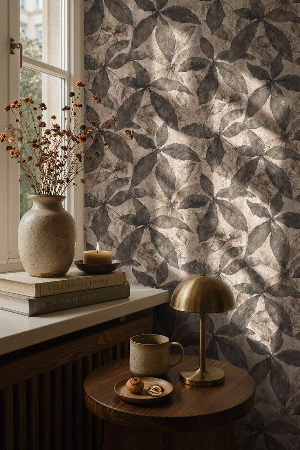 AS Creation Cosiness 793205 living room with Beige and Brown wallpaper featuring large overlapping leaf motifs; a brass table lamp and a ceramic vase are visible.