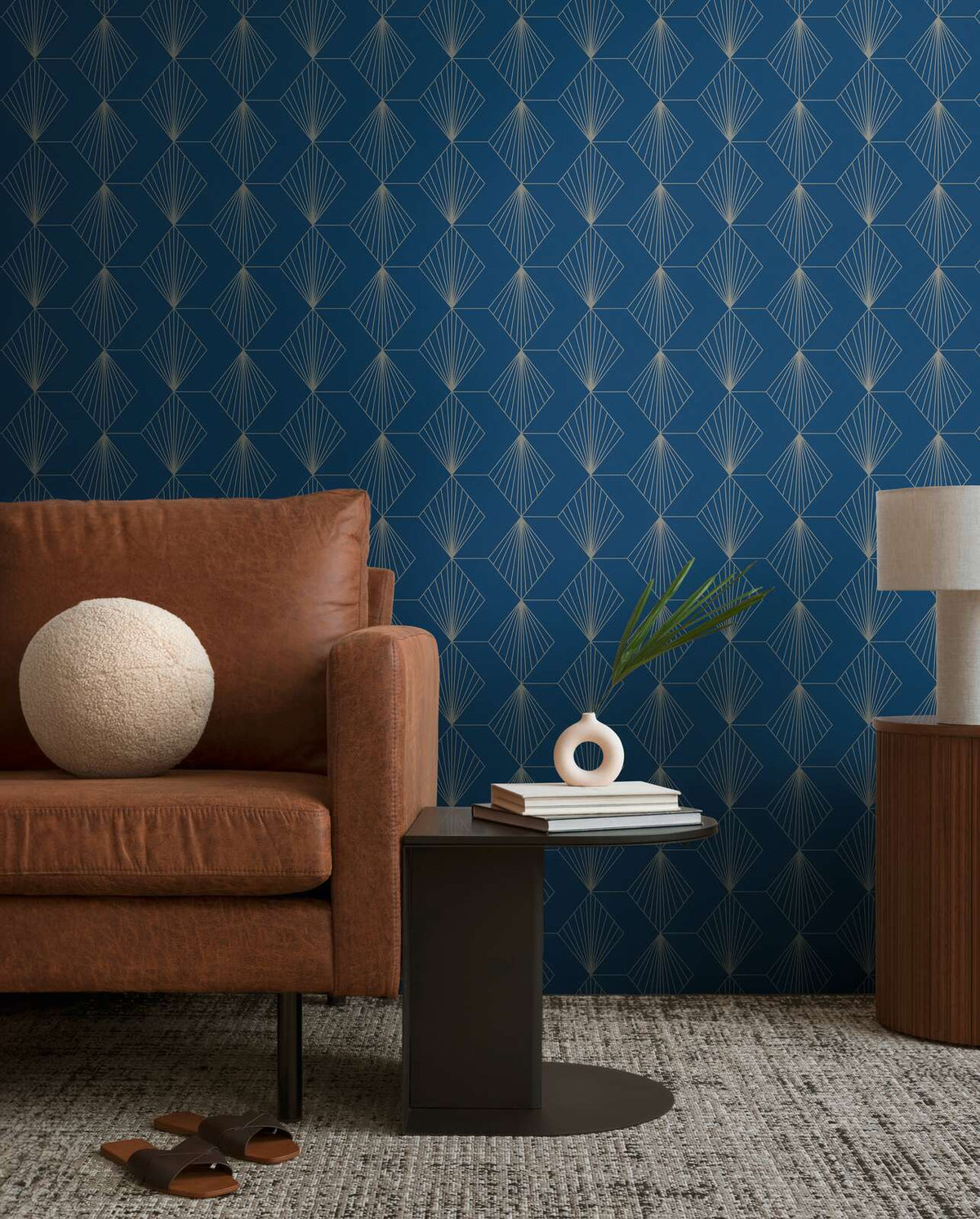 AS Creation French Affair 367102 blue geometric wallpaper with a fan motif in a living room with a sofa and a side table.