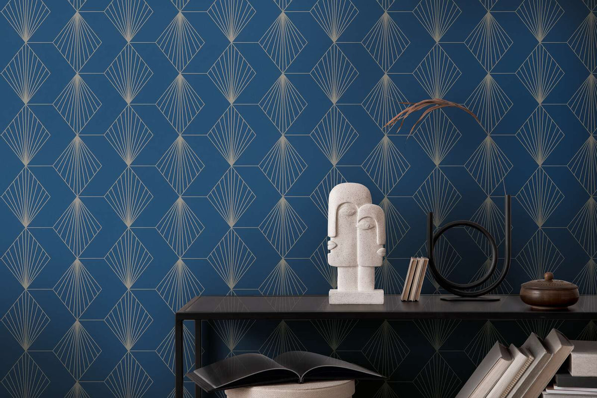 AS Creation French Affair 367102 blue geometric fan pattern wallpaper behind a dark console with a sculptural stone bust, books, and a round metal decor piece.
