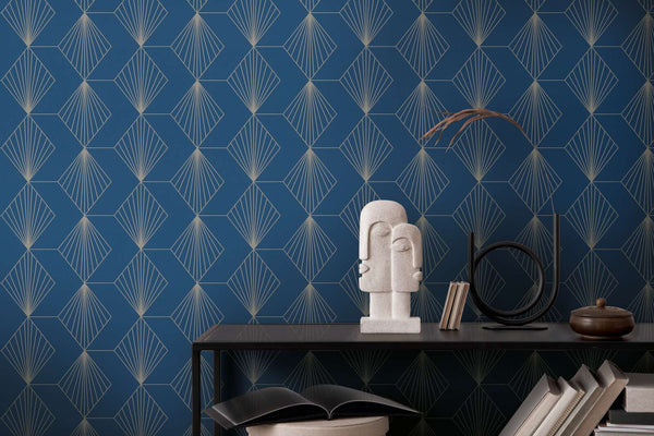 AS Creation French Affair 367102 blue geometric fan pattern wallpaper behind a dark console with a sculptural stone bust, books, and a round metal decor piece.