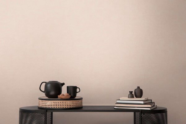 AS Creation French Affair 393417 pink wallpaper behind a black console table styled with a teapot, mug, stacked books, and small vases.
