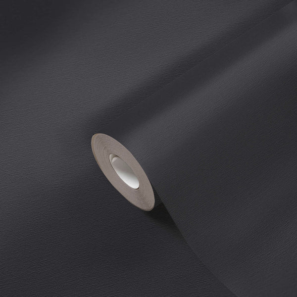 AS Creation French Affair 395726 black textured wallpaper roll on an unrolled sheet, shown in close up to reveal the fine surface grain.