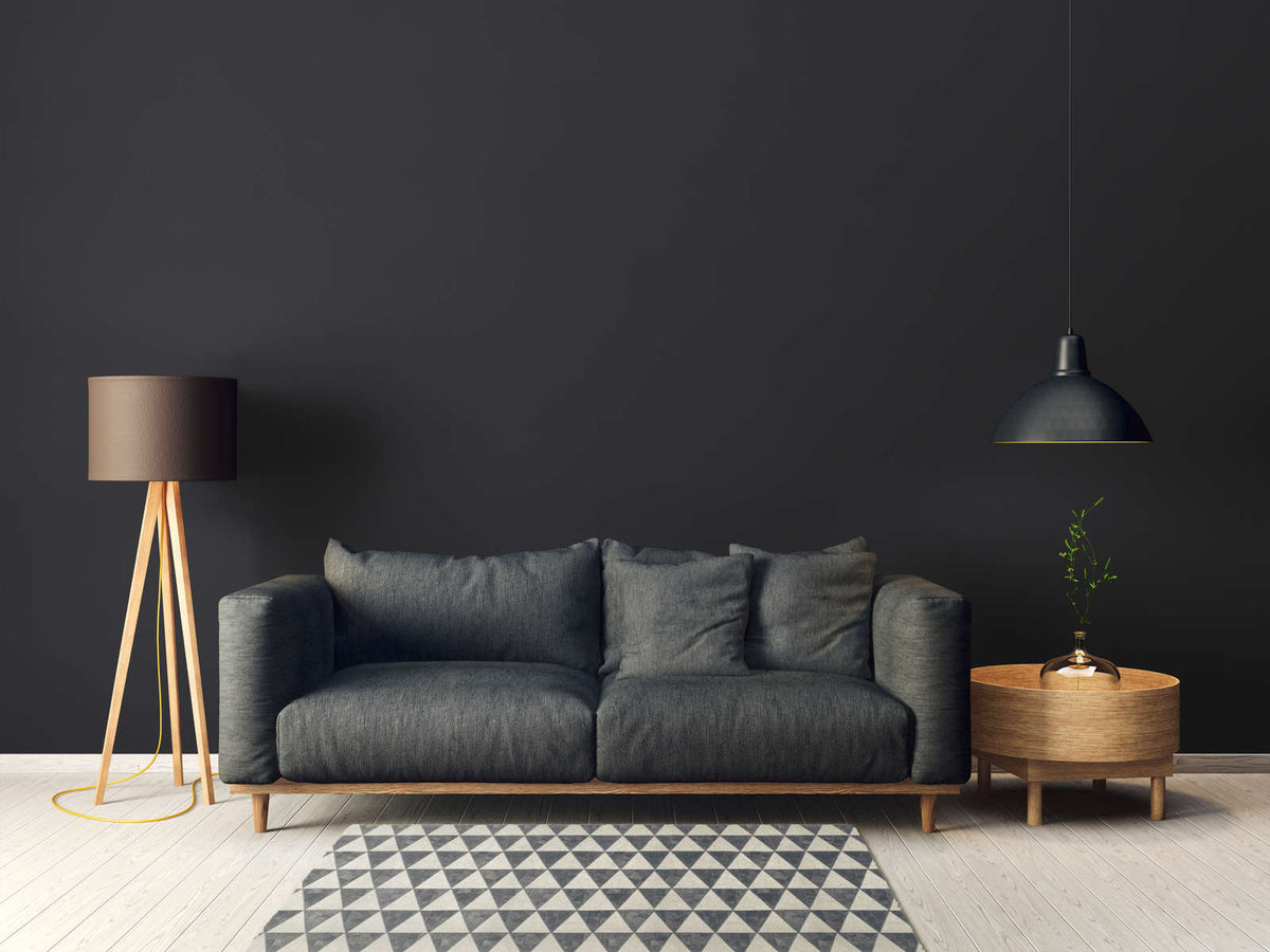 AS Creation French Affair 395726 living room with Black wallpaper behind a sofa and a floor lamp.