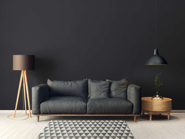 AS Creation French Affair 395726 living room with Black wallpaper behind a sofa and a floor lamp.