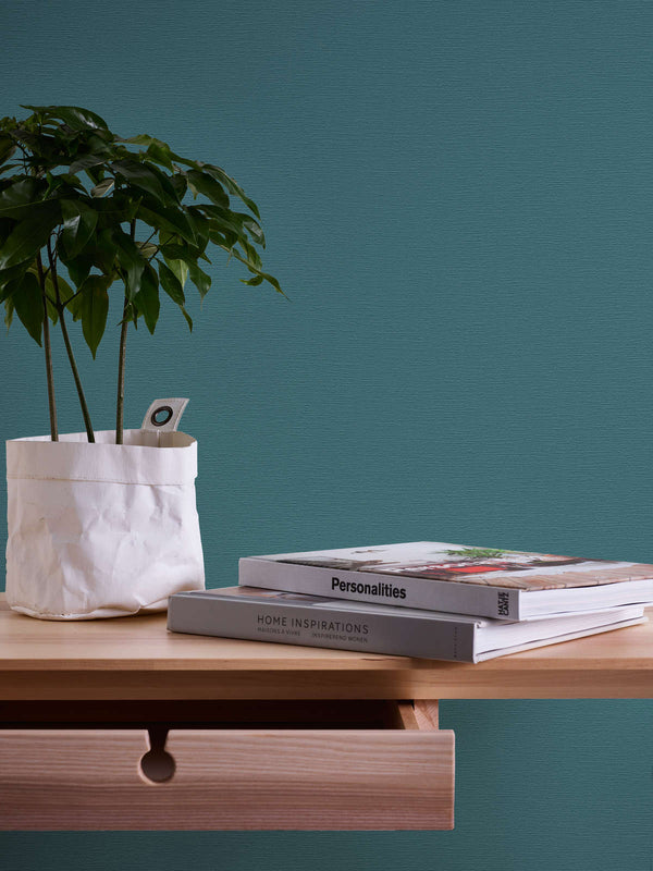 AS Creation French Affair 395764 blue, Green wallpaper with a subtle textured finish behind a wooden shelf with a potted plant and two books.