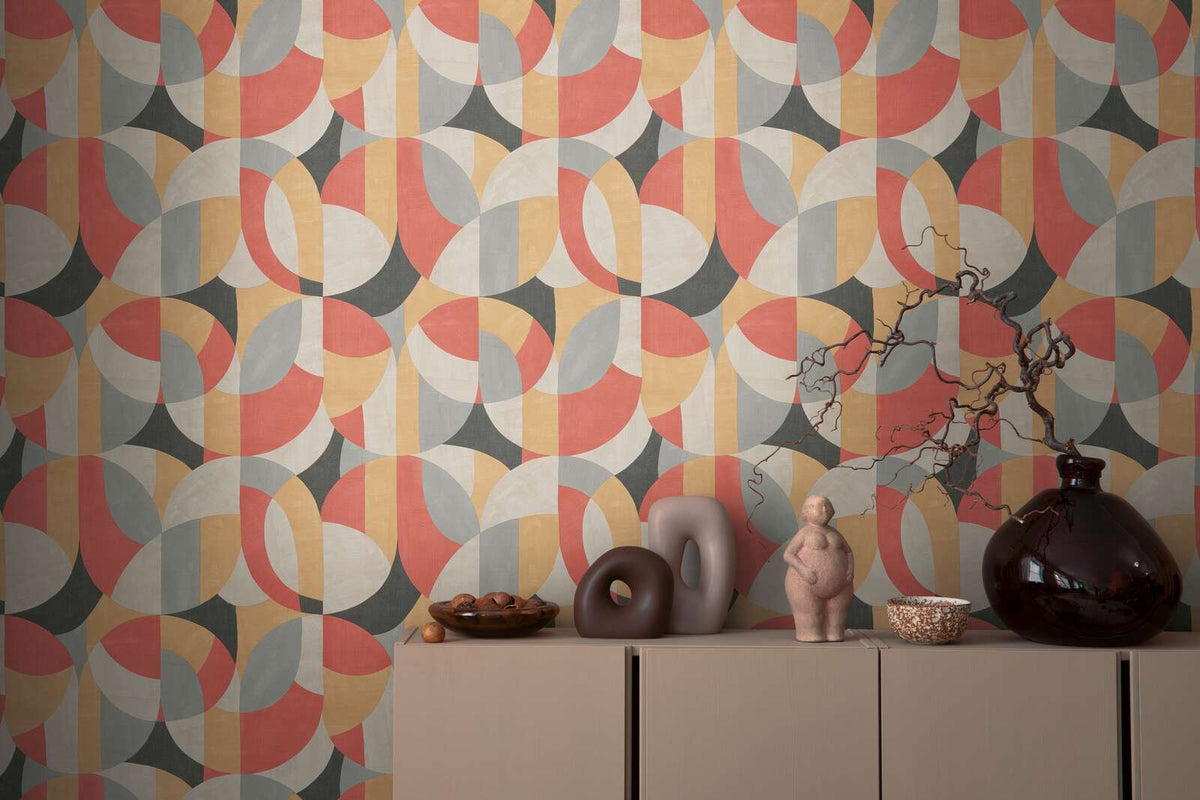 AS Creation French Affair 399323 abstract geometric circle and arc wallpaper in Beige, Black, Grey, and Red behind a sideboard with a dark glass vase, sculptural objects, and a small figurine.