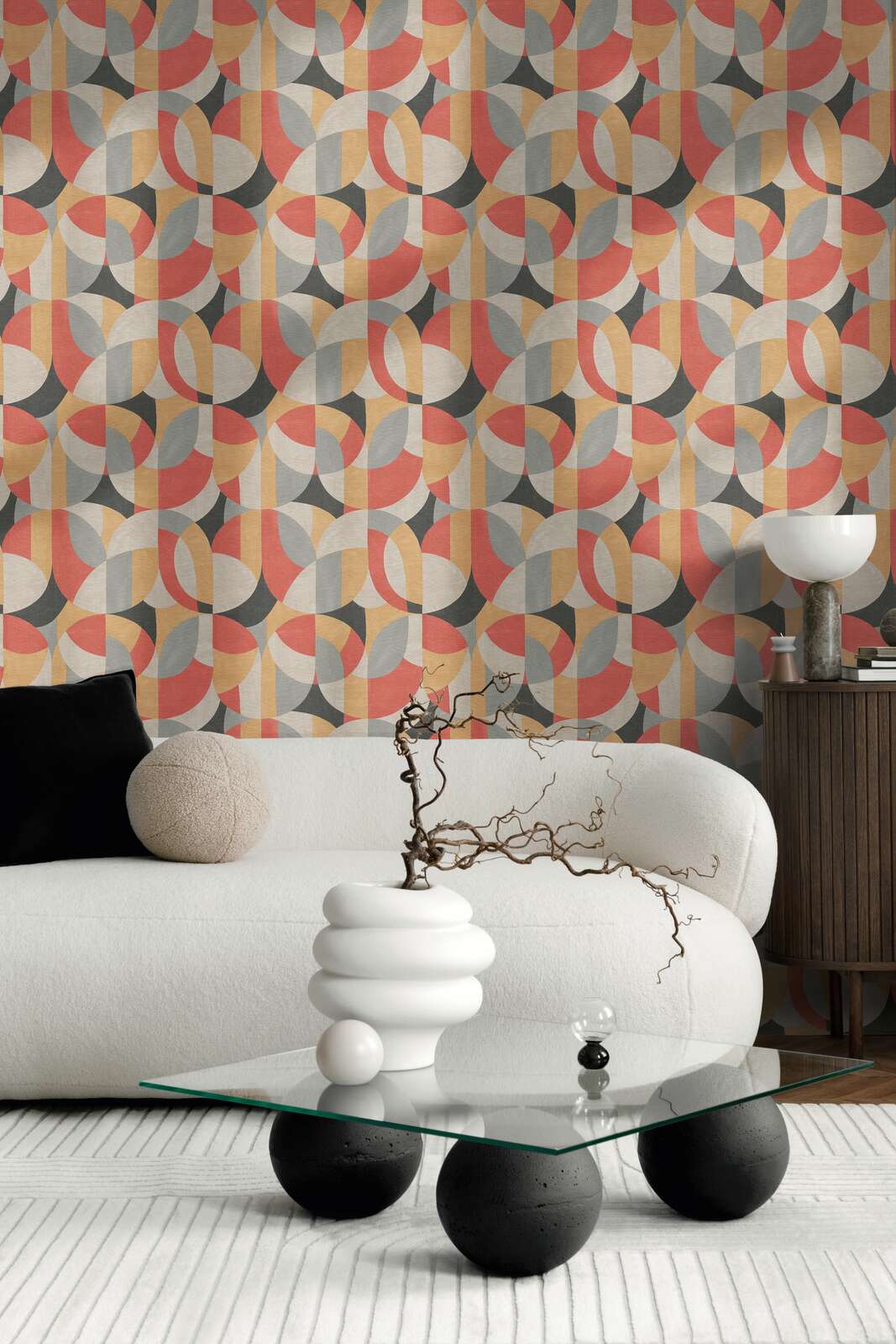 AS Creation French Affair 399323 living room with geometric wallpaper in Beige, Black, Grey, and Red behind a white sofa and a glass coffee table.