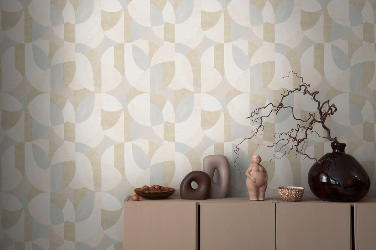 AS Creation French Affair 399324 abstract geometric wallpaper in Beige, Cream, Grey behind a cabinet topped with sculptural objects, a bowl, a small figurine, and a large glass vase with twisting branches.