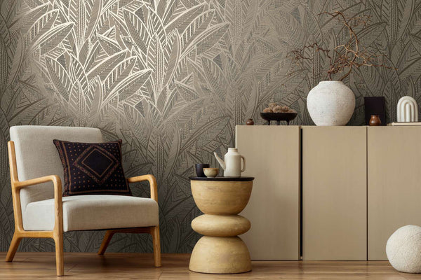 AS Creation French Affair 399332 living room with black, gold, and metallic leaf pattern wallpaper, shown with an armchair and a sideboard.