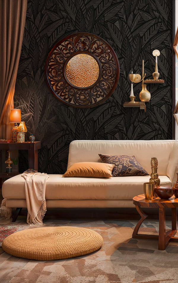 AS Creation French Affair 399334 living room with black and gold metallic leaf pattern wallpaper behind a sofa and a round wall mirror.