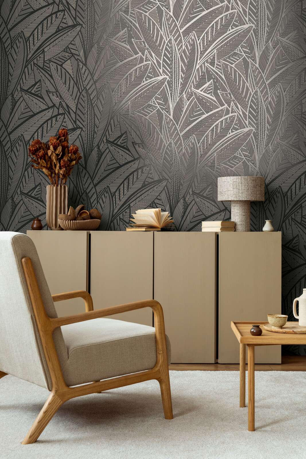 AS Creation French Affair 399334 living room with Black, Gold, Metallic leaf pattern wallpaper behind a sideboard and an armchair.
