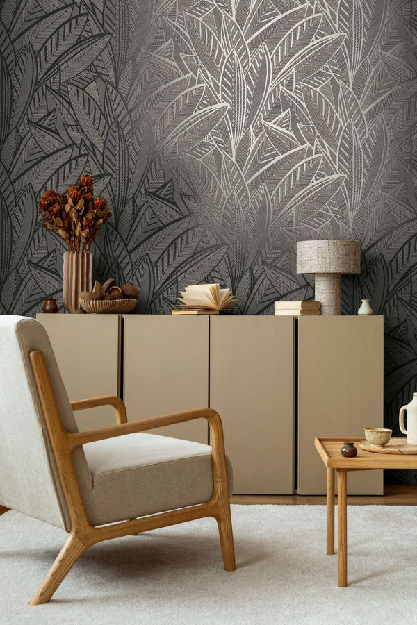 AS Creation French Affair 399334 living room with Black, Gold, Metallic leaf pattern wallpaper behind a sideboard and an armchair.