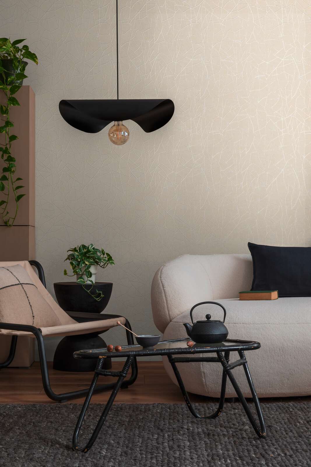 AS Creation French Affair 399342 living room with Beige, Cream, White wallpaper featuring subtle vein like lines, shown behind a light sofa and a black pendant light.