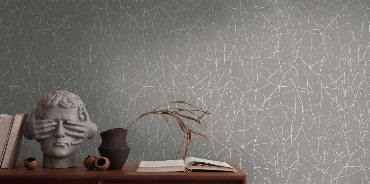 AS Creation French Affair 399343 grey and white abstract linework wallpaper behind a console styled with a sculptural bust, books, a ceramic vase with a dried stem, and an open book.