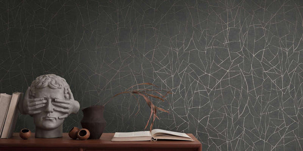 AS Creation French Affair 399344 abstract metallic gold line wallpaper on black with a console styled with a head sculpture, books, a vase with dried leaves, and an open book.