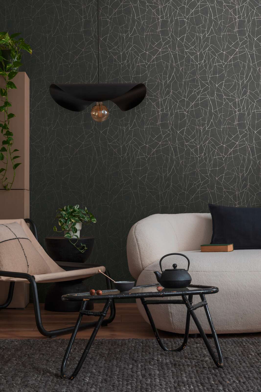 AS Creation French Affair 399344 a living room with Black, Gold, Metallic wallpaper featuring an abstract crisscross line pattern, shown behind a sofa and a coffee table.