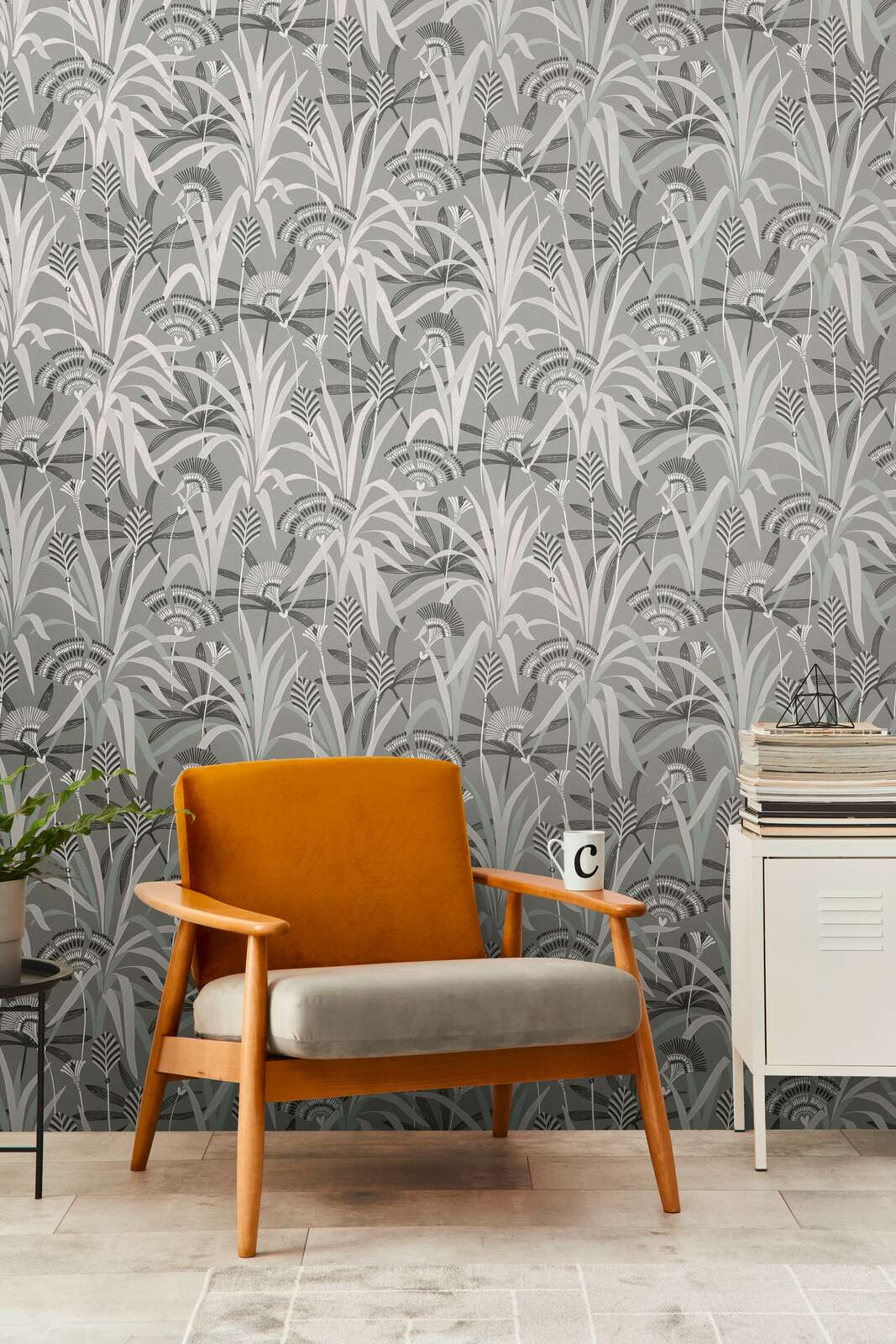 AS Creation French Affair 399362 living room with botanical wallpaper featuring layered grasses and fan like flowers, shown with a mid century armchair and a small cabinet.