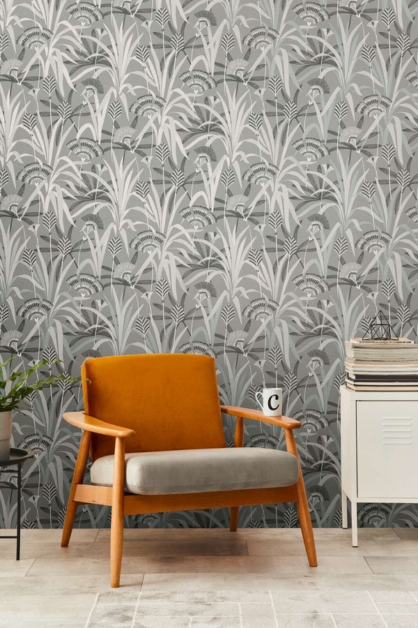 AS Creation French Affair 399362 living room with botanical wallpaper featuring layered grasses and fan like flowers, shown with a mid century armchair and a small cabinet.