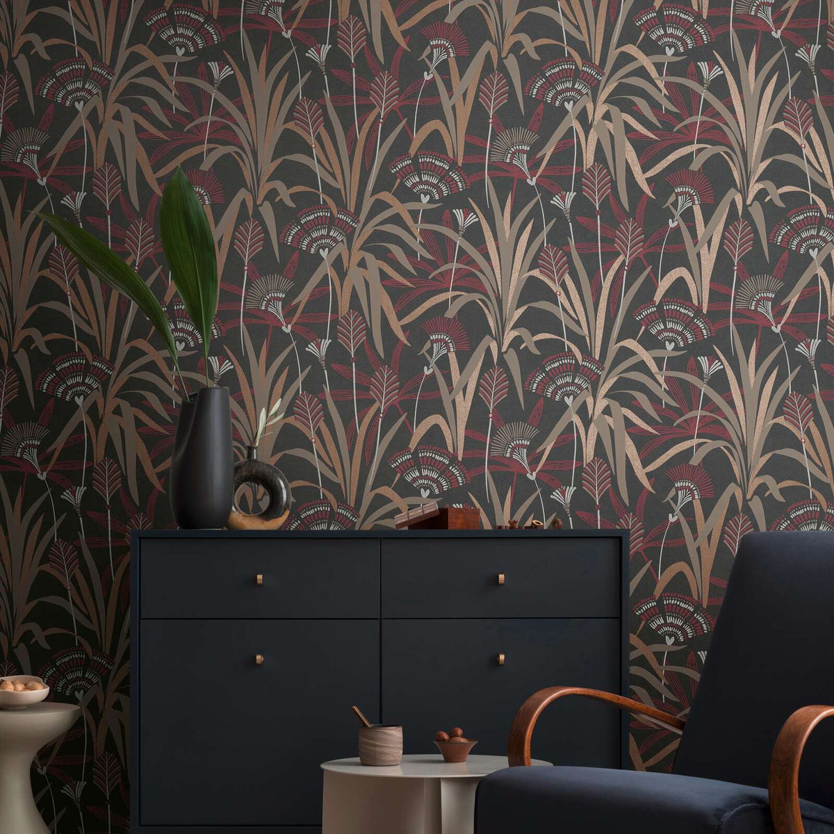 AS Creation French Affair 399364 living room with botanical wallpaper in Beige, Black, Copper, Cream, and Red, shown with a dark sideboard and an armchair.