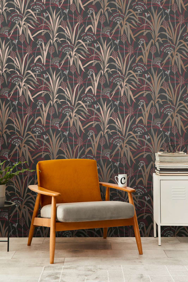 AS Creation French Affair 399364 living room with botanical wallpaper featuring stylized grasses and fan flowers in Beige, Black, Copper, Cream, and Red; a mid century armchair and a small cabinet are visible.